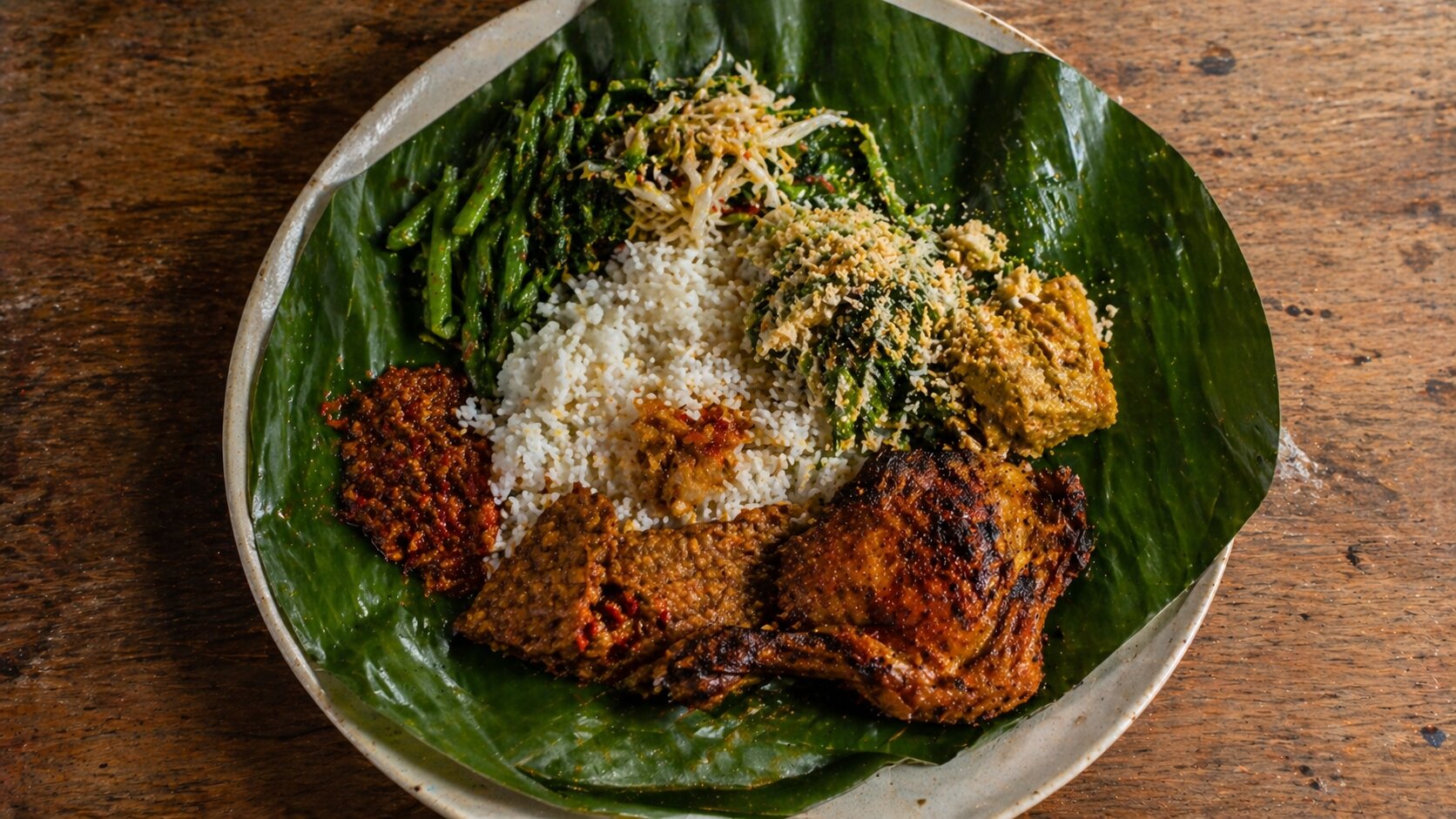 Plate of Balinese nasi campur on a wooden table at a Bali warung