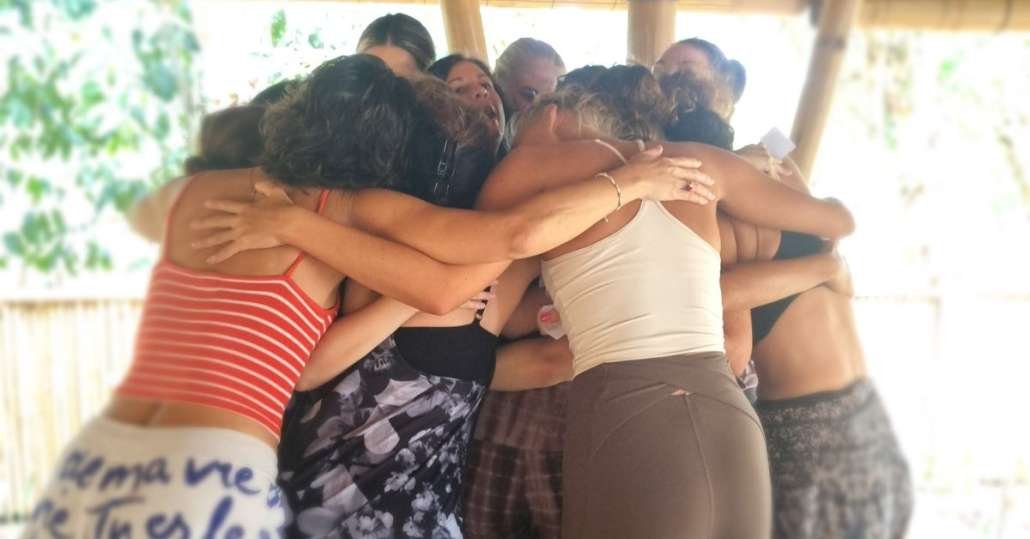 Group of students in circle huddle with arms embraced during class session