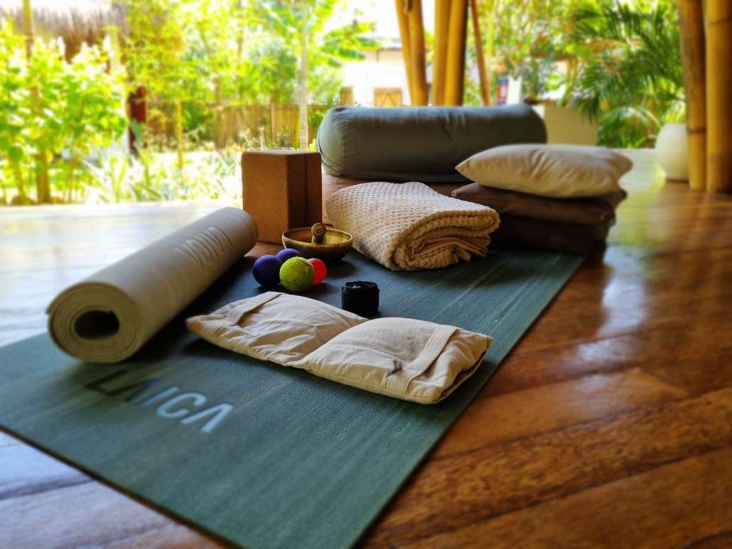 Yoga props and blankets arranged on mat in bright studio with tropical